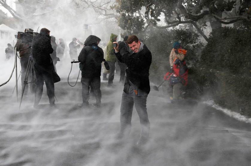 Members of the press, including NBC's Dixon, face the blowing snow caused by Marine One as it landed on the South Lawn before picking up U.S. President Barack Obama at the White House in Washington